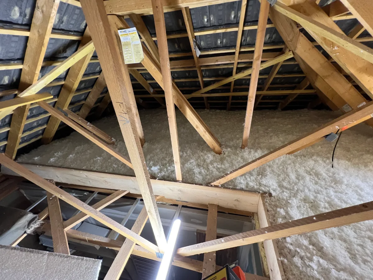 Combles perdus isolés par soufflage, avec un repère de hauteur suspendu à la charpente